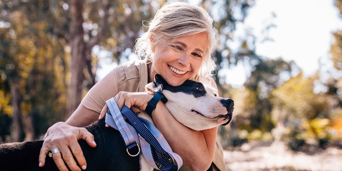 Affectionate Mature Woman Embracing Pet Dog In Nature