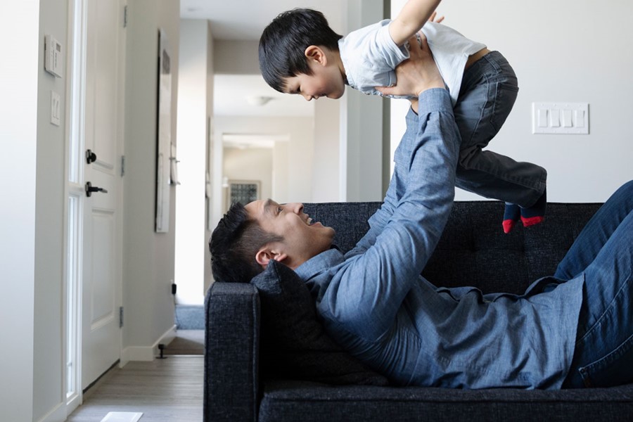 Playful Father And Son On Living Room Sofa